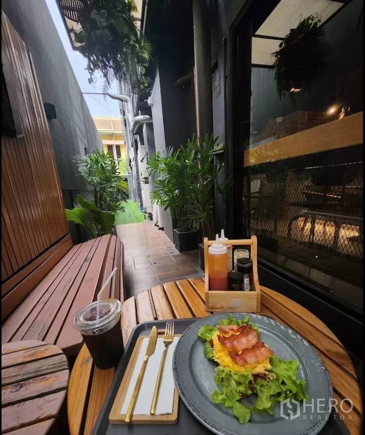 พื้นที่ขายปลีก ให้เช่าในKhlong Toei, Bangkok - ซอกนั่งเล่นกลางแจ้งแคบ ๆ มีม้านั่งบิวท์อิน กระถางต้นไม้ และโต๊ะเล็กข้างหน้าร้าน