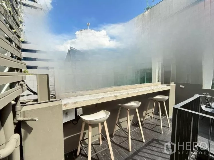 零售空间 出租在Watthana, Bangkok - 屋顶木平台上的室外吧台，配三把高脚凳，临近楼景