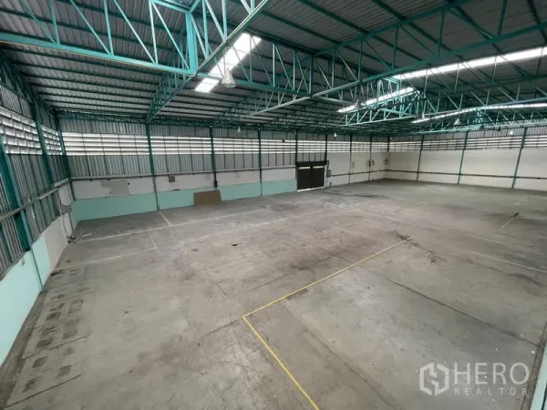 Warehouse for rent in Lat Lum Kaeo, Pathum Thani - Wide-angle view of empty warehouse space with steel beams, roller shutters and durable concrete flooring.