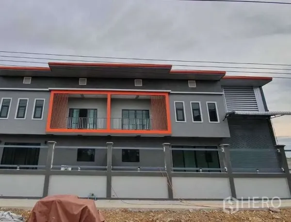货栈 出租在Pathum Thani - 现代两层仓库外立面，橙色阳台点缀与围墙