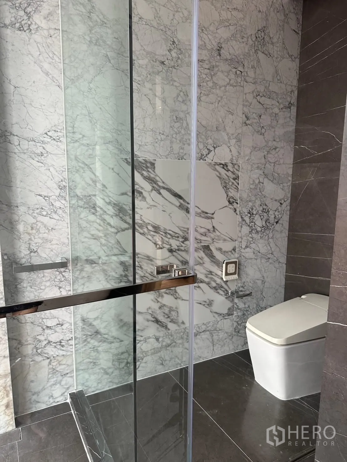 Condominium for rent or sale in Watthana, Bangkok - Marble bathroom with glass shower enclosure and modern toilet.