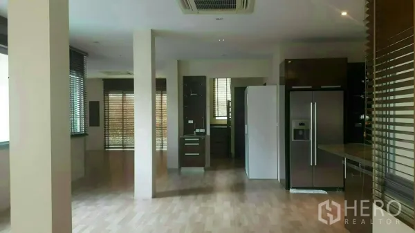Detached House for rent or sale in Prawet, Bangkok - Open-plan living and dining area with wood floors, columns, blinds and built-in kitchen.