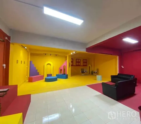 Office Space for rent in Suan Luang, Bangkok - Colorful open-plan interior with yellow and red walls, stage-like platforms and track lighting with a sofa seating area.