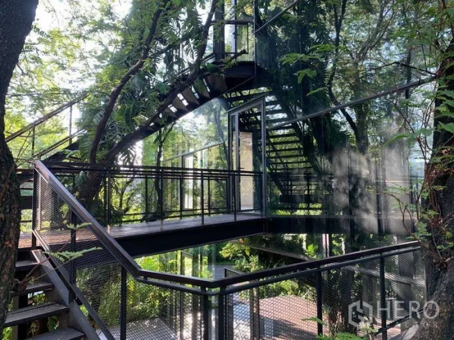 办公空间 出租在Khlong Toei, Bangkok - 多层钢楼梯与连桥围绕现代玻璃结构，四周绿意盎然。