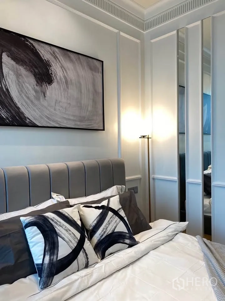 Condominium for rent in Pathum Wan, Bangkok - Close-up of padded headboard with mirrored panels and a floor lamp beside the bed.