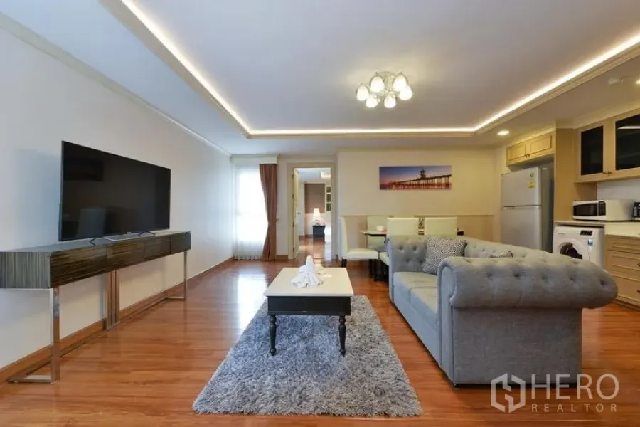 Apartment for rent in Khlong Toei, Bangkok - Wide view of open-plan lounge with sofa, coffee table, TV and access to kitchen and bedrooms.