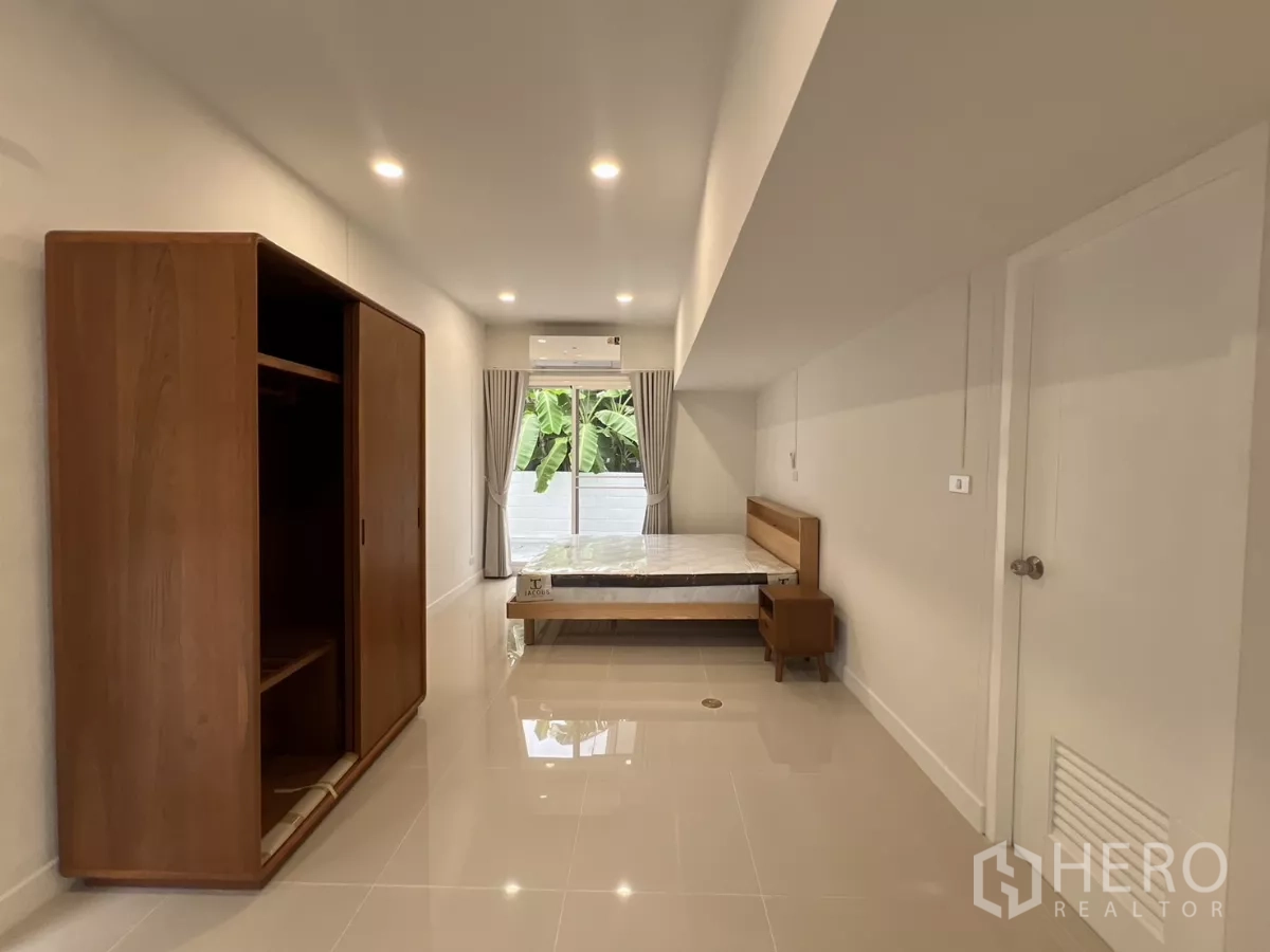 Detached House for rent in Saphan Sung, Bangkok - Ground-floor bedroom with wooden wardrobe, bed and garden-view sliding door.