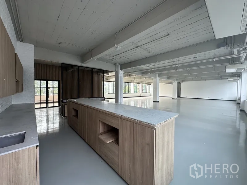 Office Space for rent - Large island counter beside expansive open-plan workspace with glossy floors.