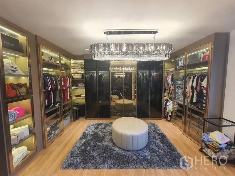 联排别墅 出售在Lat Phrao, Bangkok - 步入式衣帽间，玻璃衣柜、中央圆凳与水晶吊灯。