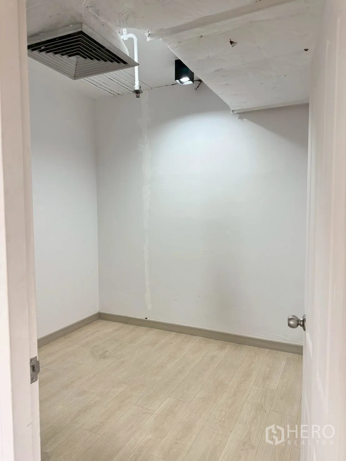 Office Space for rent in Watthana, Bangkok - Compact white room with light wood flooring and a ceiling air vent.