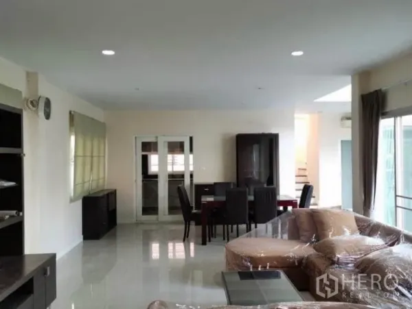 Detached House for rent in Bang Kapi, Bangkok - Open‑plan living and dining space with glossy floors, sliding glass doors and access to the staircase.