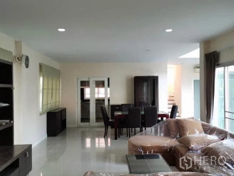Detached House for rent in Bang Kapi, Bangkok - Open‑plan living and dining space with glossy floors, sliding glass doors and access to the staircase.