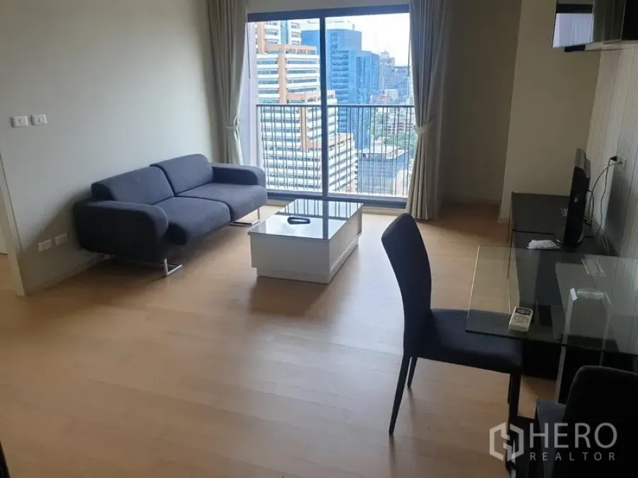 Condominium for rent in Watthana, Bangkok - Bright living room with sofa, glass dining table and balcony overlooking the Ekkamai skyline.