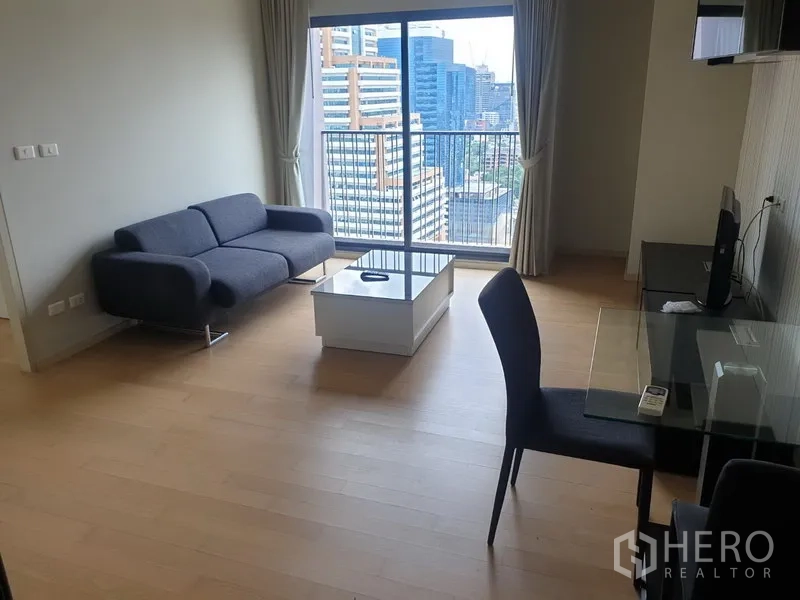Condominium for rent in Watthana, Bangkok - Bright living room with sofa, glass dining table and balcony overlooking the Ekkamai skyline.
