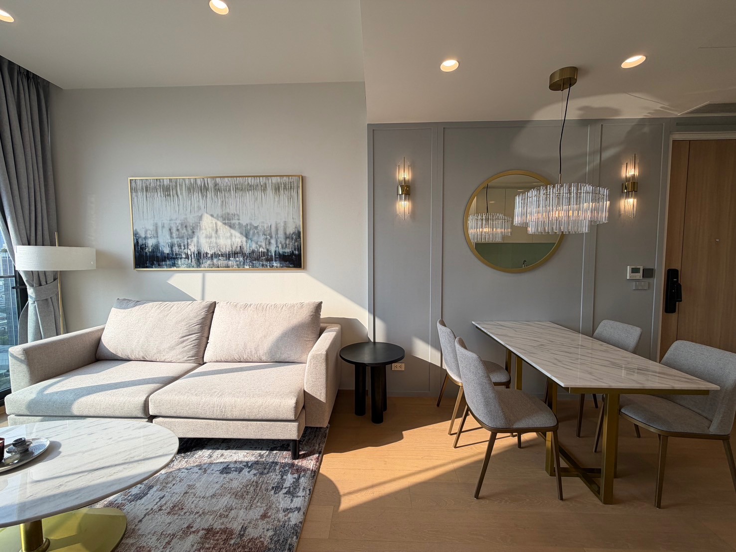 公寓 出租在Bang Rak, Bangkok - 灰色沙发搭配大理石餐桌与水晶吊灯，浅灰墙面装饰优雅。