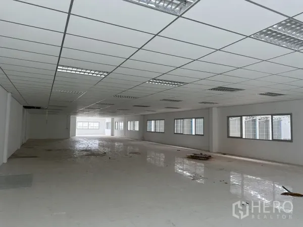 โรงงาน ให้เช่าในPathum Thani - พื้นที่สำนักงานเปิดโล่งยาว มีหน้าต่างด้านข้างหลายบานและพื้นกระเบื้อง