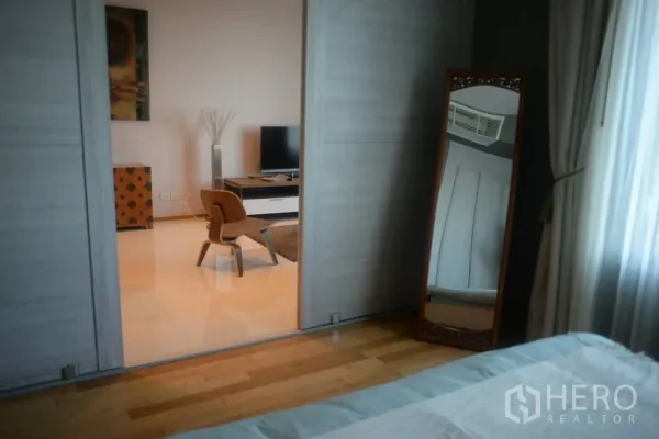 公寓 出租或出售在Khlong Toei, Bangkok - 从卧室透过推拉门望向客厅，可见电视与休闲椅。