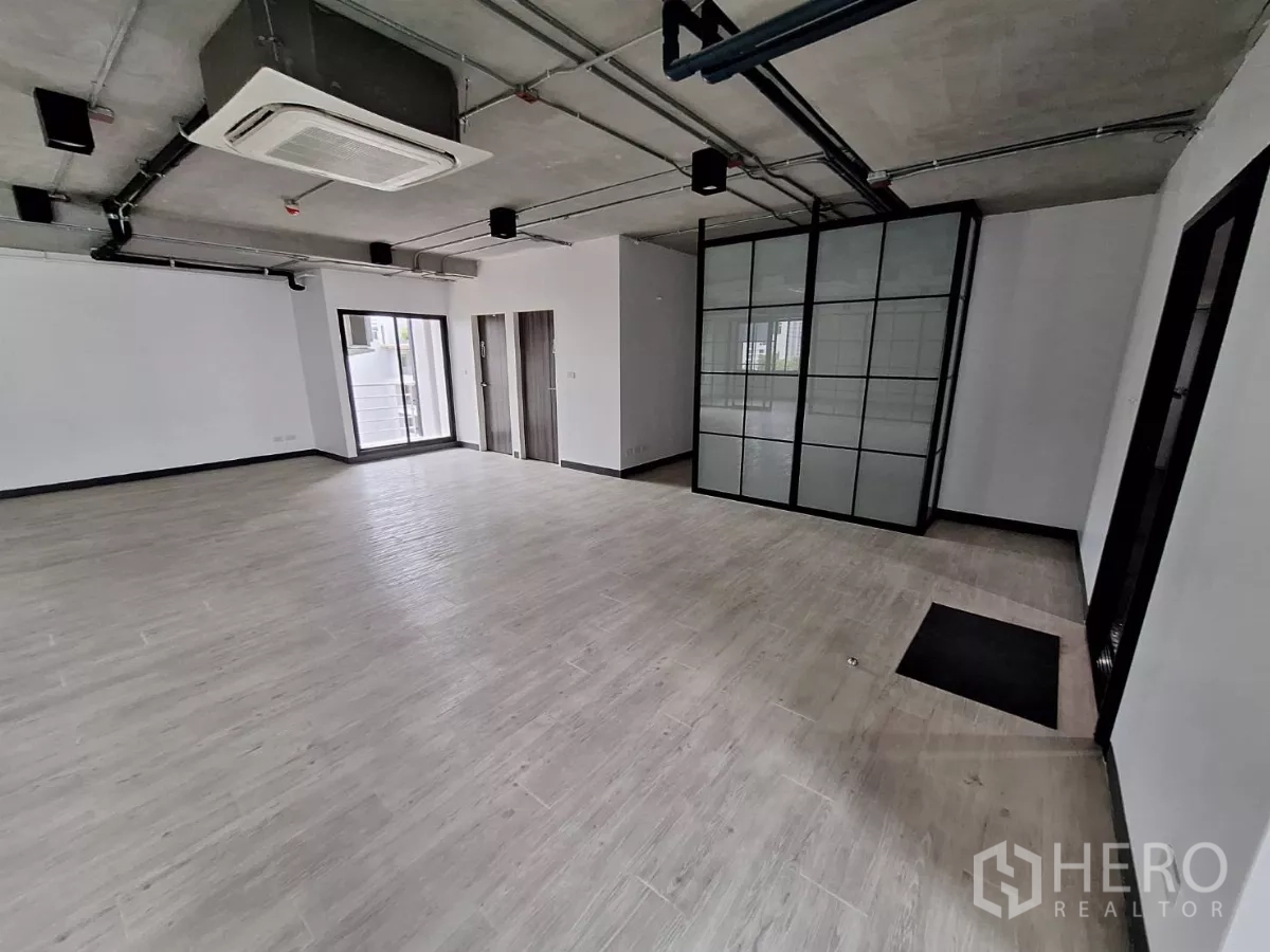 Office Space for rent in Watthana, Bangkok - Office corner showing cassette air conditioner, sliding door to balcony, and grid glass partition.