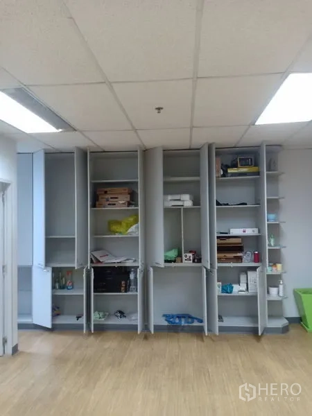 Office Space for rent - Row of tall built-in cupboards and open shelves providing ample office storage under bright lighting.