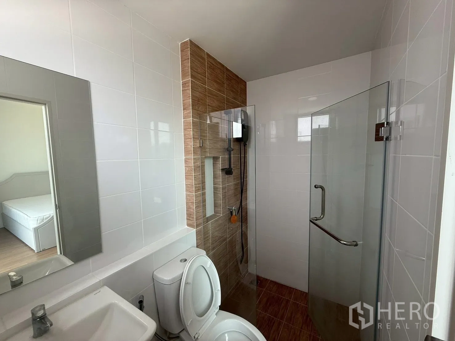 Townhouse for rent in Bang Phli, Samut Prakan - Bathroom with glass shower enclosure and wood accent tiles.