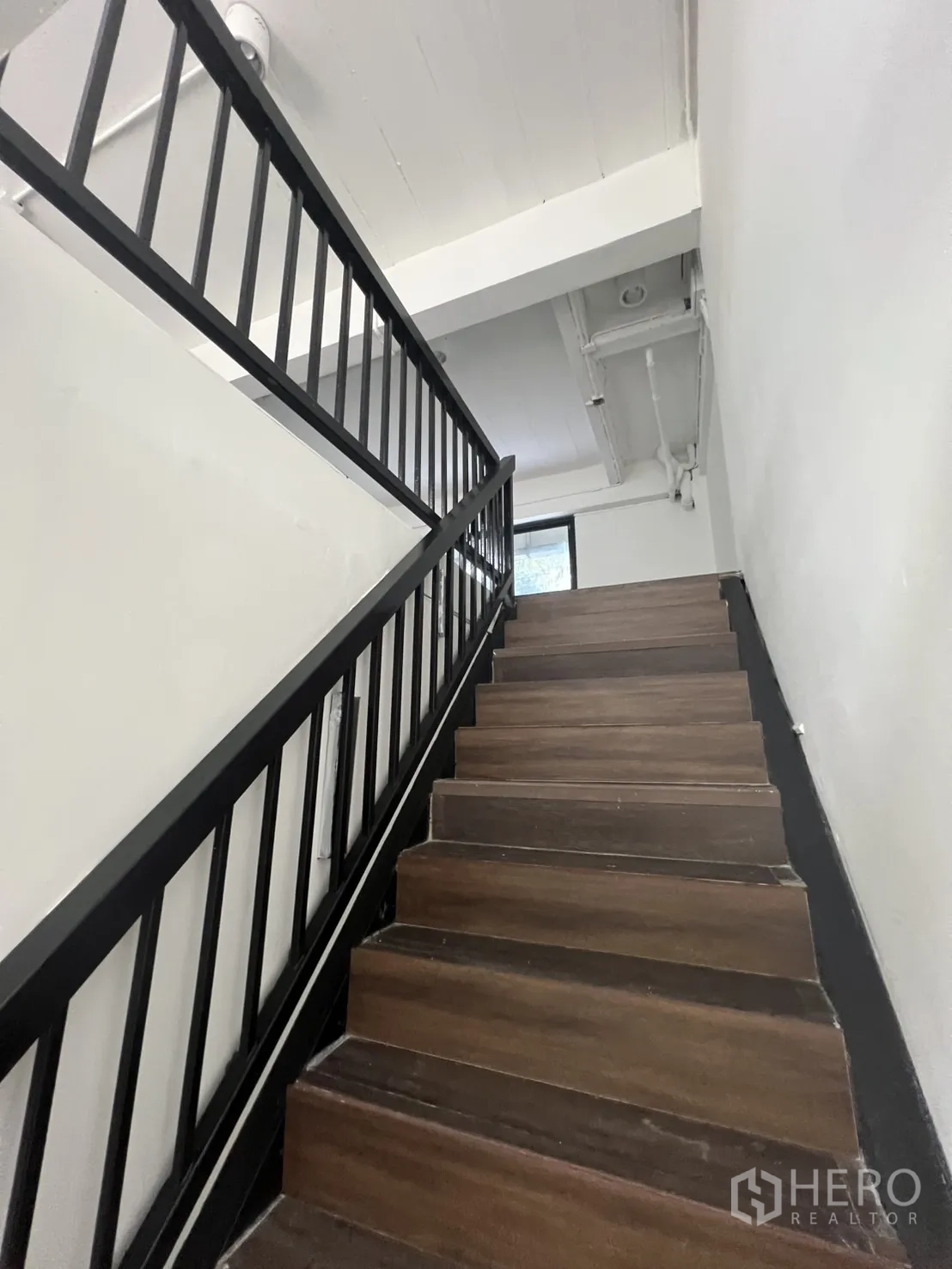 零售空间 出租在Watthana, Bangkok - 通往夹层的木质台阶与黑色栏杆楼梯。