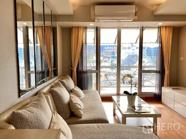 คอนโด ขายในKhlong Toei, Bangkok - ห้องนั่งเล่นสว่างด้วยหน้าต่างบานใหญ่ เชื่อมต่อระเบียง โซฟาตัวแอลและโต๊ะกลาง ในคอนโดเขตคลองเตย ใกล้ BTS อ่อนนุช