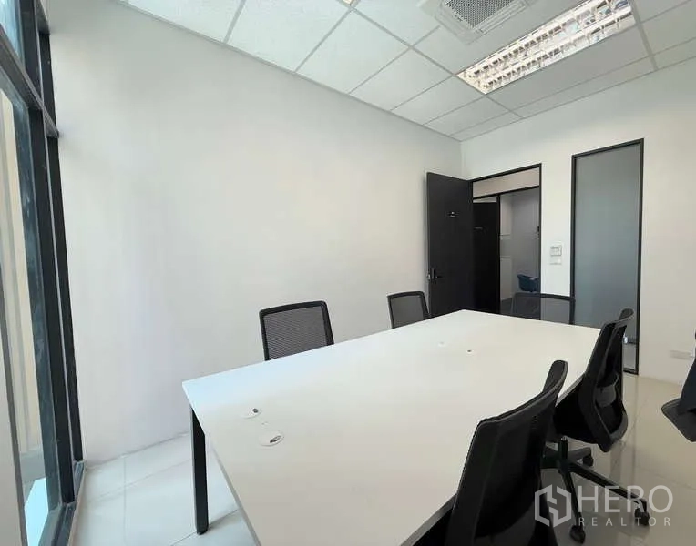 办公空间 出租在Huai Khwang, Bangkok - 明亮的会议室，白色长桌、网面椅与嵌入式空调，旁有落地窗。