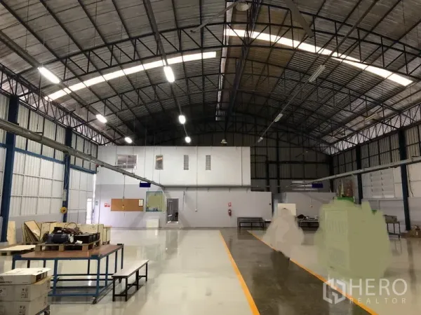 Factory for sale in Pathum Thani - Production hall facing an internal two‑storey office block under bright lighting.