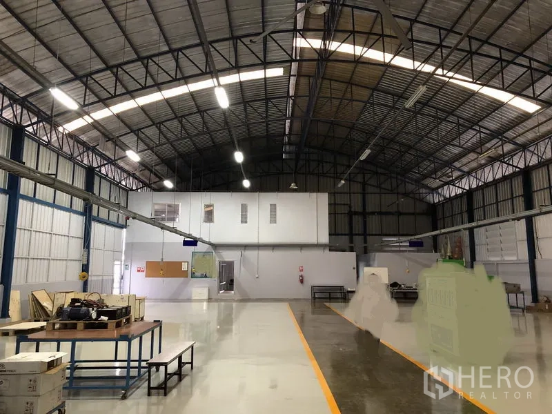 Factory for sale in Pathum Thani - Production hall facing an internal two‑storey office block under bright lighting.