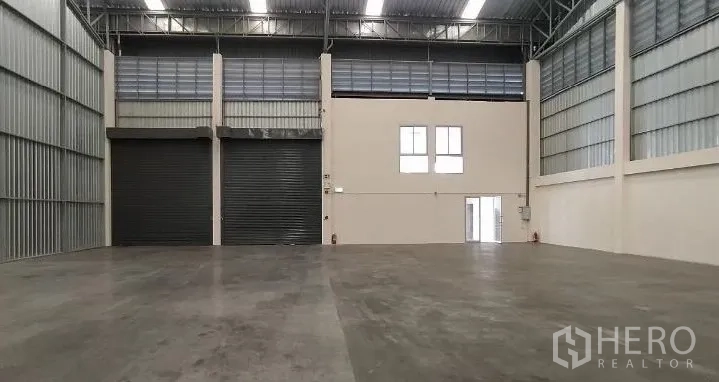คลังสินค้า ให้เช่าในSamut Prakan - พื้นที่โกดังโล่งกว้างพร้อมประตูม้วนขนาดใหญ่สองบานและหน้าต่างชั้นลอย