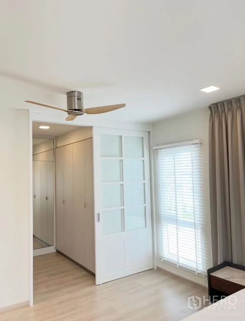Detached House for rent in Bang Phli, Samut Prakan - Bedroom with ceiling fan, sliding door to closet, and large windows with blinds.