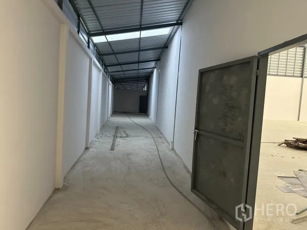 工厂 出租在Nong Khaem, Bangkok - 侧边有顶走廊，金属屋面与白色墙体，设有安全钢门通往仓库。