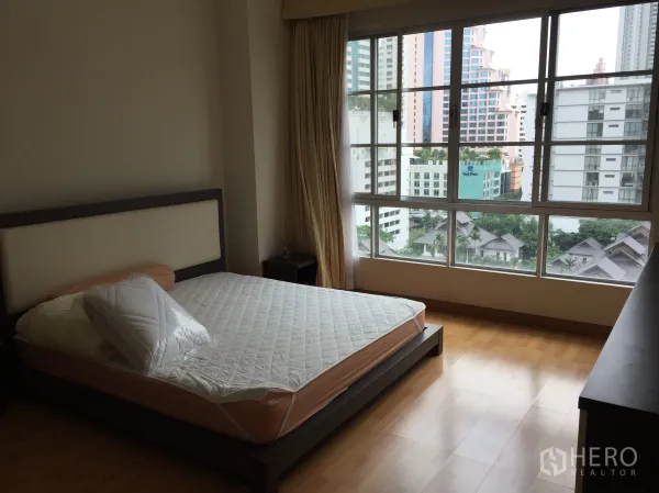 Condominium for rent in Khlong Toei, Bangkok - Bedroom with large picture windows offering city view and natural light.