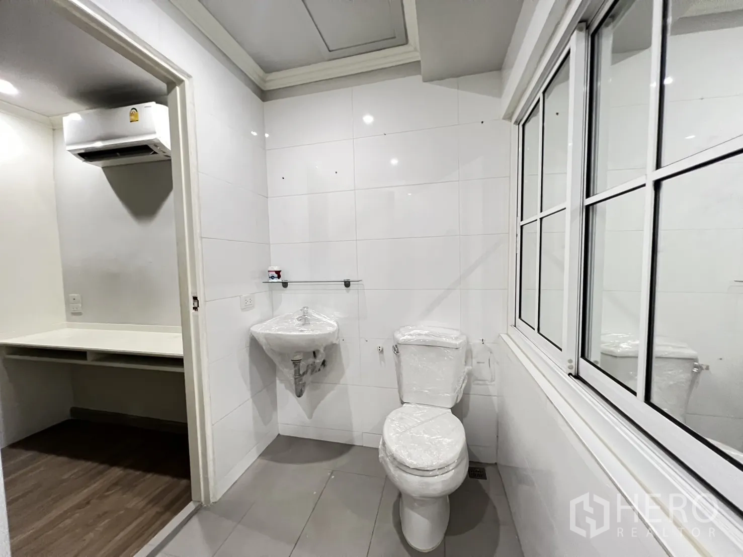 店屋 出租在Bang Rak, Bangkok - 紧凑卫生间，带坐厕与洗手盆，旁有带空调的小工作区。