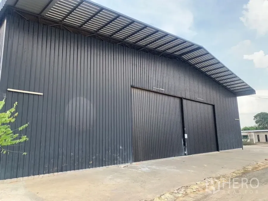 货栈 出租在Khan Na Yao, Bangkok - 黑色金属外墙的仓库外观，宽大型推拉门与带雨棚的装卸区。