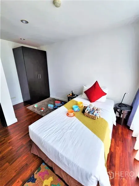 公寓 出租在Bang Rak, Bangkok - 温馨卧室，单人床、深色衣柜与木地板。