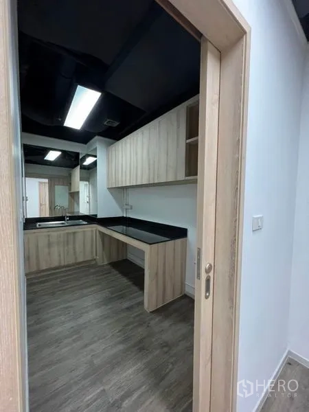 办公空间 出租在Khlong Toei, Bangkok - 茶水间，L型黑色台面、水槽与浅木色橱柜