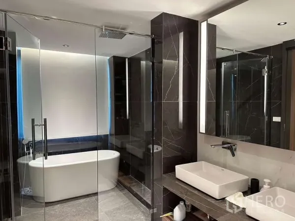 Townhouse for rent in Yan Nawa, Bangkok - Modern bathroom with freestanding bathtub, glass shower and dark marble walls.