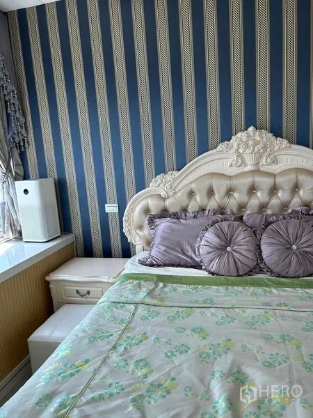 Condominium for sale in Huai Khwang, Bangkok - Primary bedroom with ornate tufted headboard and blue striped feature wall.