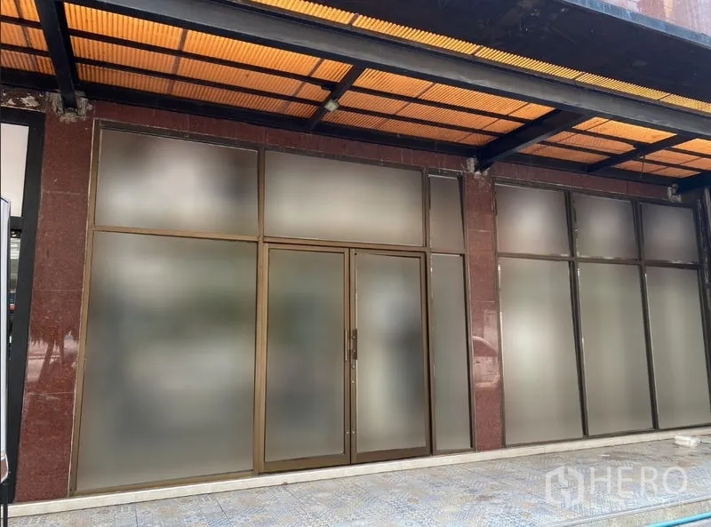 零售空间 出租在Watthana, Bangkok - 街铺外立面，宽幅磨砂玻璃与双开门，带遮雨棚走道。