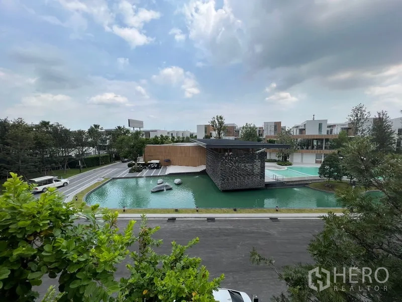 Detached House for rent or sale in Saphan Sung, Bangkok - Community clubhouse beside a landscaped pond with walkways and greenery.