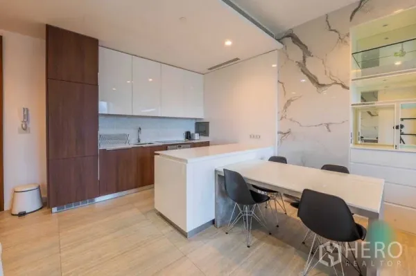 Condominium for rent in Pathum Wan, Bangkok - Open kitchen and dining area with an island breakfast bar and four black chairs by a marble feature wall and shelving.