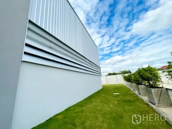 คลังสินค้า ขายในLam Luk Ka, Pathum Thani - ผนังโกดังติดช่องลม โดยมีแถบสนามหญ้าและกระถางต้นไม้เรียบร้อย