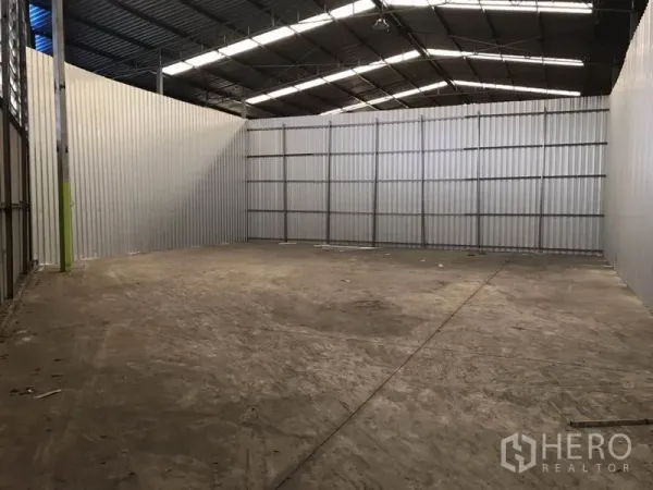 Warehouse for rent in Bang Na, Bangkok - Spacious empty warehouse bay with corrugated metal walls, high steel truss roof and concrete floor.