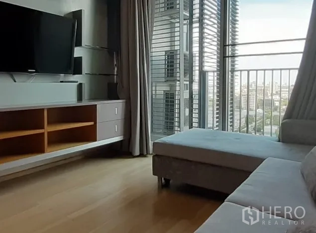 คอนโด ให้เช่าในKhlong Toei, Bangkok - ห้องนั่งเล่นสว่าง โซฟา ตู้ทีวี และระเบียงเปิดรับวิวเมือง