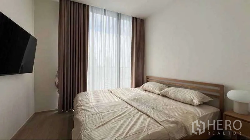 คอนโด ให้เช่าในWatthana, Bangkok - ห้องนอนมีหน้าต่างบานใหญ่ ผ้าม่านสีน้ำตาล ทีวีติดผนัง และโต๊ะข้าง