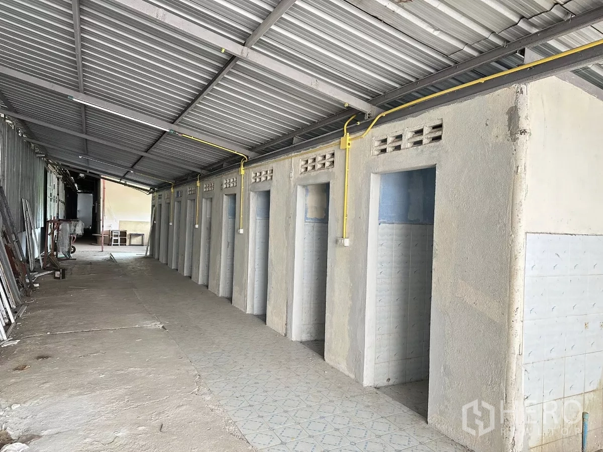Warehouse for sale in Nong Chok, Bangkok - Row of tiled restroom and shower cubicles under a metal canopy in the service zone.