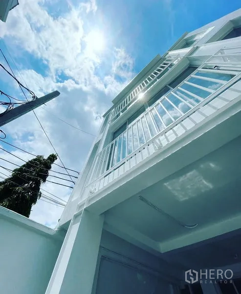 店屋 出售在Din Daeng, Bangkok - 仰视三层白色店屋立面，设阳台，蓝天下通透明亮。