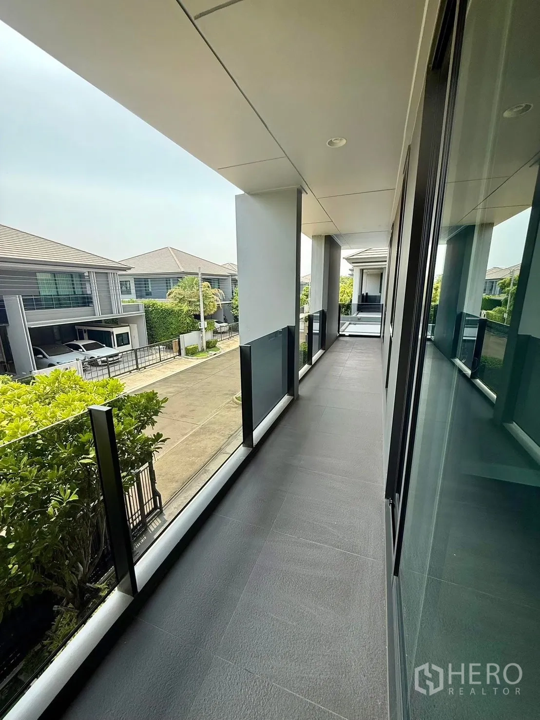 Detached House for rent in Bang Kapi, Bangkok - Long covered balcony with glass railing overlooking a quiet residential street.