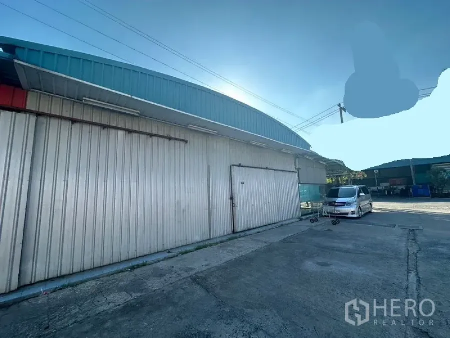 Warehouse for rent in Saphan Sung, Bangkok - Rear corrugated metal wall with a sliding warehouse door and wide driveway.